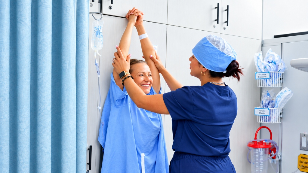 Patient achieving full overhead shoulder mobility with assistance after Advanced Capsular Mobilization procedure